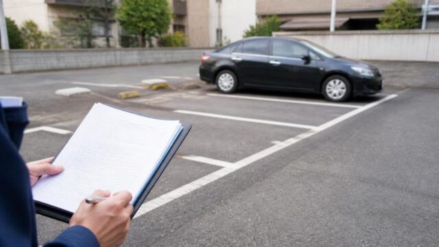 月極駐車場の契約書類と駐車区画を確認する様子